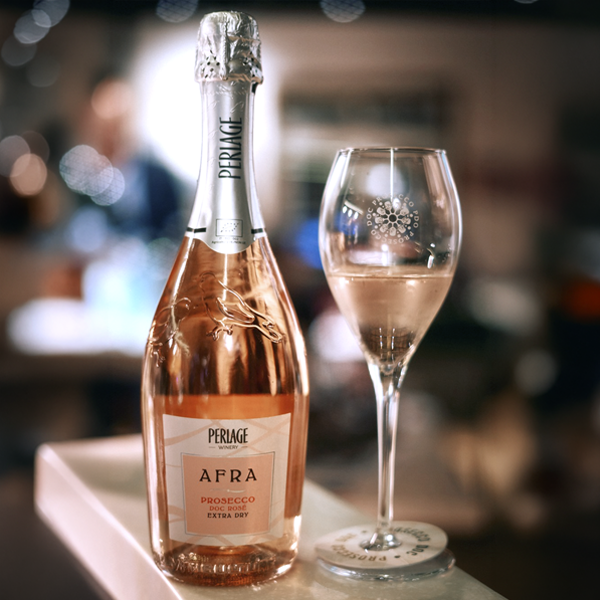 Botella de Afra Prosecco Rosé de Perlage junto a dos copas de vino espumoso rosado.