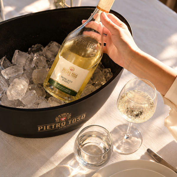 Pietro Toso Moscato d’Asti en cubitera con hielo junto a una copa de vino.